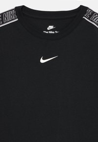 Black Nike t-shirt with white swoosh logo centered on chest and "NIKE" text along shoulder seams.