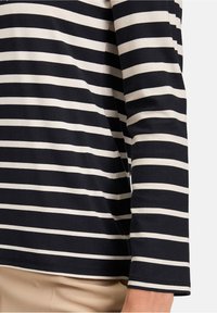 Gestreiftes langärmliges Oberteil in Navy und Creme mit lockerer Passform, aus weichem Material und mit Rundhalsausschnitt. Mit geraden Ärmeln akzentuiert.