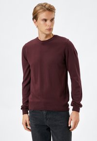 Bordeaux sweatshirt met lange mouwen, geribbelde halslijn en manchetten, gemaakt van gebreid stof met een gladde textuur. Draag het met donkere jeans.