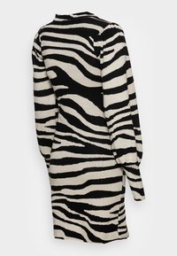 Robe noire et crème à manches longues avec un motif à rayures zébrées, dotée d'un col montant et de manches bouffantes. Texture en maille douce. Détail fendu sur le côté.