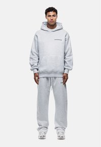 Set di felpa e pantaloni della tuta grigi realizzato in morbido tessuto, con tasca frontale e logo stampato sul petto. Vestibilità rilassata e polsini elasticizzati.