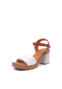 Sandalo da donna con una fascia in pelle bianca, una cinghia alla caviglia color nocciola e un tacco a blocco rivestito in suede grigio chiaro. Base della piattaforma marrone per un'altezza extra.