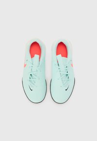 Baskets de sport bleu clair avec des accents noirs, semelles blanches et semelles intérieures corail. Comprend des lacets et un logo Nike distinctif sur le côté.