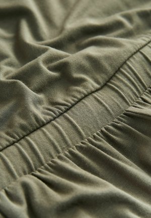 Olivazöld anyag, puha textúrával, összegyűrt gumival a varrás mentén, amely fodros hatást kelt a felületen.