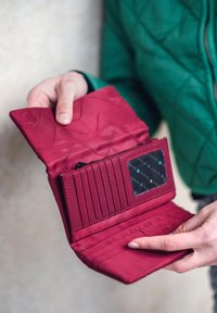 Red quilted wallet with a textured exterior, featuring card slots, a zip pocket, and a transparent ID window.