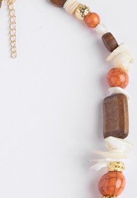 Kralenketting met houten, oranje, gouden en witte componenten in verschillende vormen en texturen, waaronder een rechthoekig houten stuk.