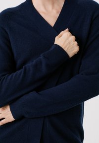 Cardigan avvolgente blu navy in morbido tessuto a maglia, con scollatura profonda a V, maniche lunghe e una vestibilità rilassata con polsini a coste.