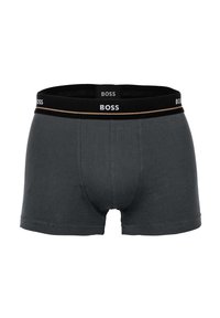 Graue Baumwoll-Boxershorts mit einem schwarzen Bund, der den Markennamen "BOSS" und einen goldenen Akzentstreifen trägt. Weicher Stoff, figurbetontes Design.