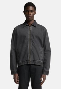 Svart denimjacka med dragkedja fram, spetskrage och två sidfickor. Tyget har en lätt textur och en klassisk passform.