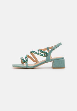 Aqua suede block-heel sandal with a strappy design, decorated with green and blue embellishments on the straps and a cushioned footbed.
