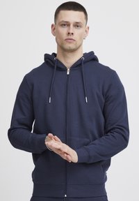 Marine blauwe rits hoodie van een katoenmix, voorzien van een capuchon, voorzakken en zilverkleurige hardwareaccenten. Zachte textuur met ribgebreide manchetten en tailleband.