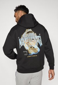 Must must, millel suur graafika trükk seljas, millel on "Manchester City," keerukad mustrid ja koordinaadid. Pehme kangas, mugav lõige.