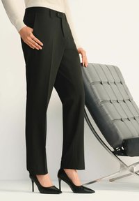 Czarne dopasowane spodnie o prostej nogawce, z bocznymi kieszeniami i gładkim wykończeniem. Noszone z czarnymi szpilkami w szpic.