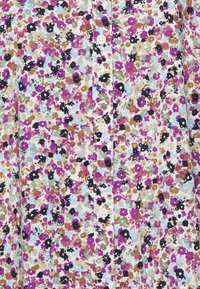 Bloemmotief stof shirt met kleine, multikleuren bloemen in roze, blauw en bruin op een lichte achtergrond, met witte knopen langs de voorkant.