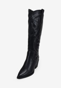 Botín de cuero negro hasta la rodilla con punta afilada, tachuelas decorativas de plata y un tacón ligeramente curvado. Presenta un patrón texturizado a lo largo del tubo.