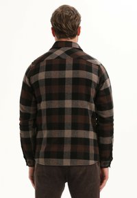 Bruin en zwart geblokt flanellen shirt met een traditionele kraag, knoopmanchetten en een afgeronde zoom. Zachte textuur met een duidelijk ruitpatroon.