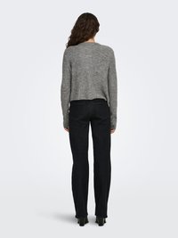 Gray knit sweater with a rounded neckline, cropped length, and long sleeves paired with dark high-waisted jeans and black heels.