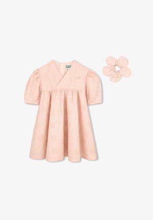 Robe de bébé rose pâle à manches bouffantes avec motif géométrique argenté, accompagnée d'un chouchou assorti en forme de fleur.