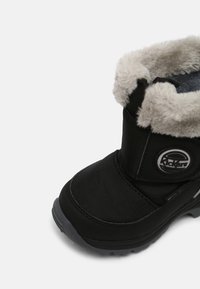 Schwarzer Winterstiefel mit strukturiertem Stoff, flauschigem grauem Innenfutter, gepolstertem Schaft und Gummisohle. Verfügt über ein rundes Logo an der Seite.