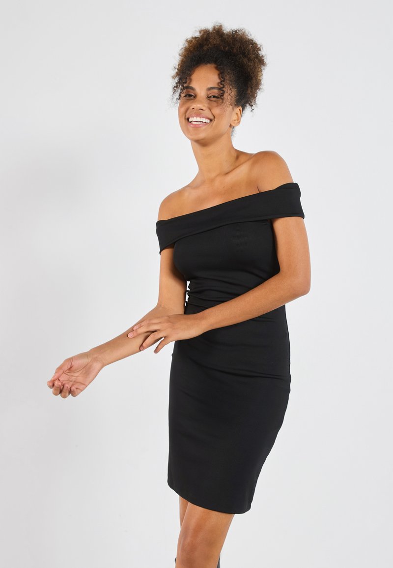 Musta olkaimeton bodycon-mekko, jossa on ribbikuvio, tiukka malli ja polvipituus, esitellen sileää siluettia ja eleganttia kaula-aukkoa.