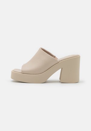 Beige læder højhælede mules med åben tå, en tyk platform og en kraftig blokhæl. Glat tekstur og minimalistisk design.