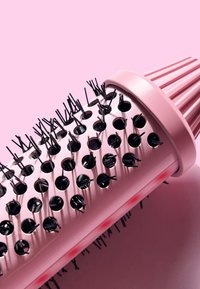 Brosse à cheveux ronde avec un manche rose clair et des poils noirs. Dispose de trous régulièrement espacés le long du baril pour un meilleur débit d'air. Poignée texturée.