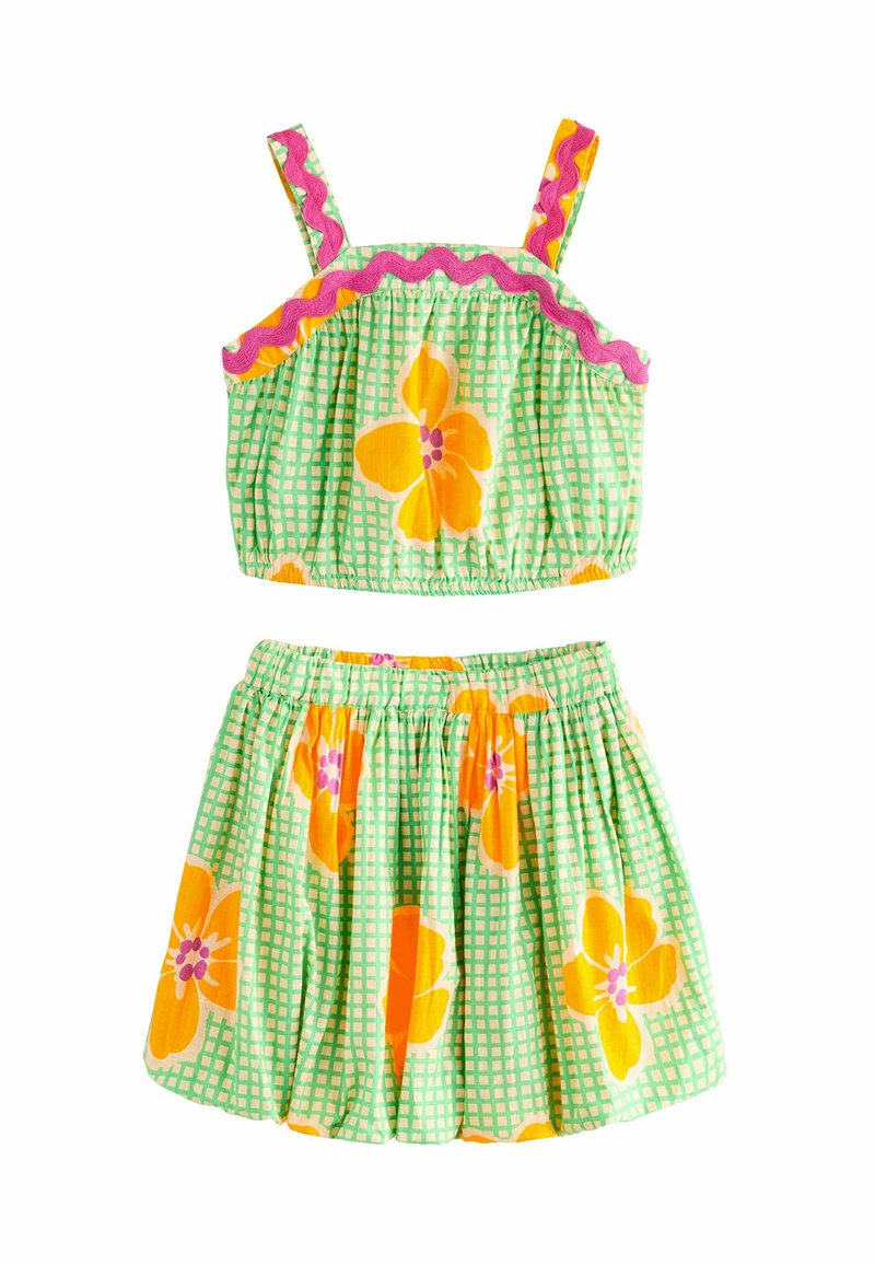 Ensemble floral deux pièces composé d'un crop top à carreaux verts et d'une jupe évasée assortie, orné de fleurs orange et violettes éclatantes.