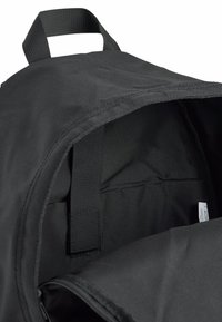 Svarte ryggsekkens interiør har en glatt stoffforing, justerbare stropper og en sidelomme. Designet er minimalistisk uten mønstre.