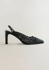 Escarpin slingback en cuir tressé noir avec bout pointu, talon de hauteur moyenne et boucle dorée sur la bride de cheville, sur fond uni.