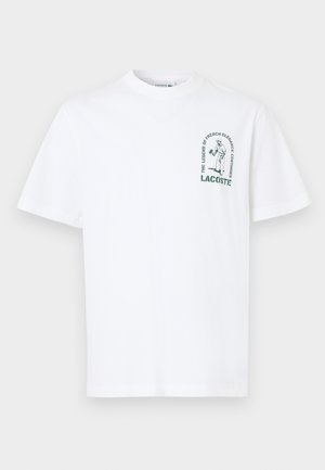 T-shirt bianco in cotone con maniche corte, colletto rotondo e una stampa grafica verde che raffigura un tennista e del testo sul lato sinistro del petto.