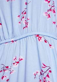 Světlemodré šaty s květinovými vzory v růžové a bílé barvě, s elastickým pasem vytvářejícím jemné řasy. Měkká, lehká látka.