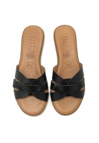 Schwarze Rutschsandalen mit zwei überkreuzten Riemen über einem tan-farbenen strukturierten Fußbett, das eine glatte Oberfläche und eine flache Sohle aufweist.