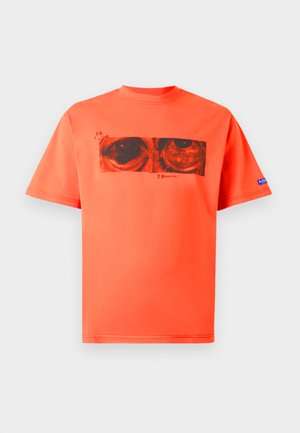 Tricou cu mânecă scurtă din bumbac portocalie vibrant, cu un print grafic cu ochi negri pe față, având un decolteu rotund cu nervuri.