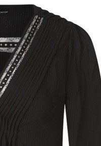 Zwarte top met lange mouwen, verticale plooien, een V-hals en een decoratieve strook met zilveren studs langs de halslijn.