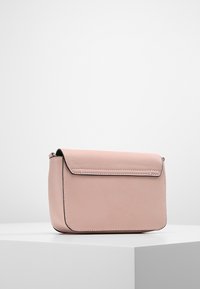Růžová kožená taška přes rameno s klopou. Vyznačuje se čistými liniemi, šití a obdélníkovým tvarem. Hladká textura a minimální kovové doplňky.