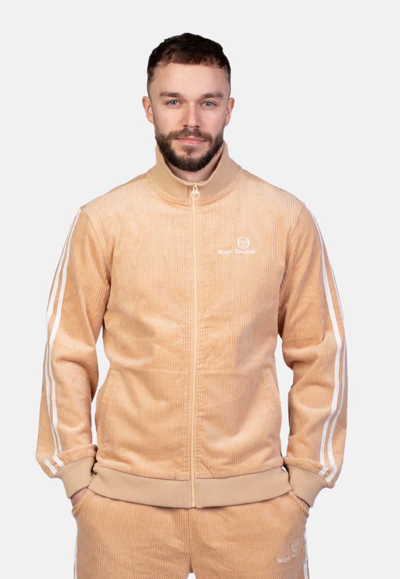 Giacca in velluto a coste pesco con zip, con strisce bianche lungo le maniche, colletto e polsini a costine, caratterizzata da un logo sul petto sinistro.