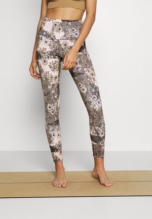 I leggings a vita alta presentano un motivo floreale e paisley in tonalità di marrone e rosa, realizzati in un tessuto elasticizzato con una superficie liscia.