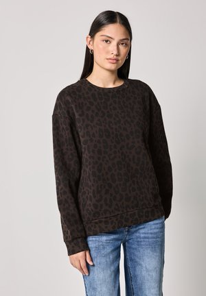 Felpa marrone con stampa leopardata nera, scollatura rotonda, maniche lunghe e polsini a costine, abbinata a jeans blu. Tessuto morbido.