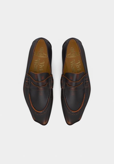 Ζευγάρι σκούρα καφέ δερμάτινα μοκασίνια με μυτερά δάχτυλα και ραμμένη λεπτομέρεια, εμφανιζόμενα από πάνω σε ανοιχτό φόντο.