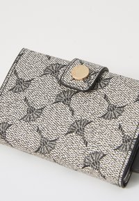 Black and white wallet with floral pattern, textured material, snap closure, and gold hardware accent. Compact design.