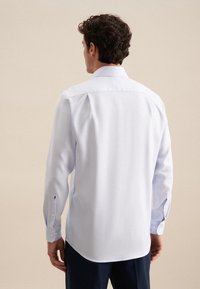Camicia da uomo a maniche lunghe blu chiaro, con una texture liscia, polsini con bottoni e colletto classico. Presenta spacchetti laterali e un design posteriore pulito.