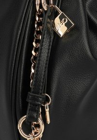 Black leather bag detail with gold chain strap and small gold padlock engraved with "LIU JO" brand logo.