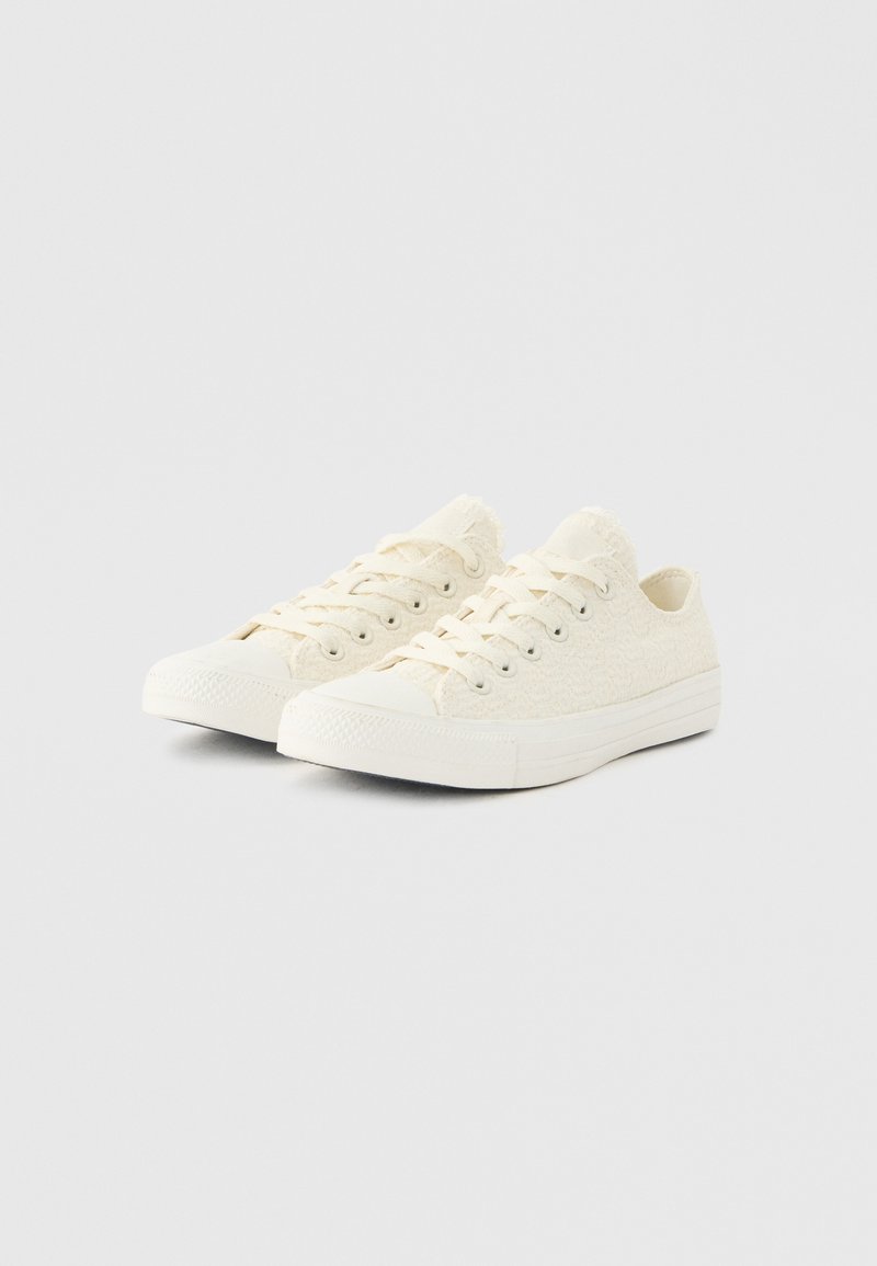 Sneakers bianche basse con dettagli in pizzo, suole in gomma e lacci bianchi, mostrati affiancati su uno sfondo chiaro.