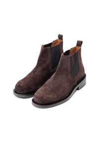 Bottines Chelsea en suède marron avec des panneaux latéraux élastiques et des languettes, présentant un bout arrondi élégant et un petit talon en caoutchouc noir.