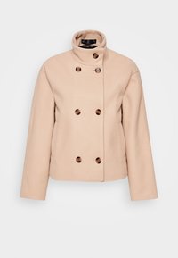 Manteau court en laine beige avec col montant et six grands boutons en écaille de tortue en style croisé sur fond blanc.