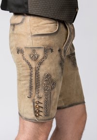 Knielange, beiges Leder-Shorts mit filigraner schwarzer Stickerei, dekorativen Knöpfen und einer strukturierten Oberfläche.