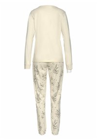 Light beige long-sleeve top, paired with cream pajama pants featuring a floral pattern in green, pink, and black, gathered at ankles.