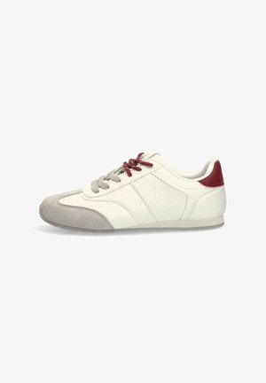 Zapatilla deportiva de perfil bajo en blanco y gris con parche rojo en el talón, cordones rojos y beige, y suela texturizada mostrada en perfil lateral.