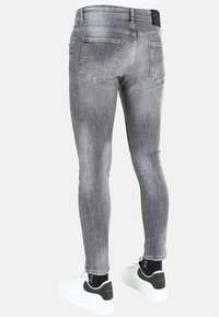 Dunne grijze jeans van denim, met een vervaagde afwerking, standaard achterzakken en gecombineerd met witte sneakers.