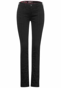 Černé džíny s úzkým střihem, které mají přední kapsy, zapínání na knoflík a hladkou strukturu. Pásek má kontrastní logo.